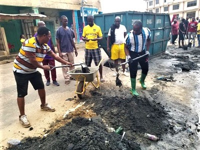 Daasebre Kwaku Boateng (right), the Omanhene of New Juaben, with shovel desilting choked gutters. With him are some residents of the area